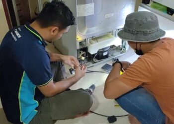 MUHAMMAD Allami Zainuddin (kiri) bersama Abdul Raftri Abdullah memberi perkhidmatan membaiki alat elektrik secara percuma di rumah mangsa banjir di Taman Inderapura, di Kuantan, Pahang. - FOTO/DIANA SURYA ABD. WAHAB