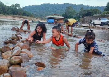 SEKUMPULAN kanak-kanak sedang menyusun batu dan mandi di kawasan cetek Sungai Tembeling selepas banjir surut di Kuala Tahan di Jerantut, Pahang. -  UTUSAN/HARIS FADILAH AHMAD