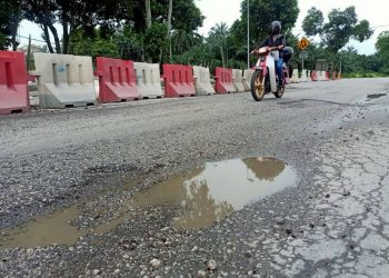 PENUNGGANG motosikal melalui jalan raya yang rosak di sekitar Persiaran Hamzah Alang, Kapar, Klang, Selangor pada 28 Disember lalu. – GAMBAR HIASAN/UTUSAN