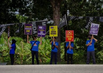 Sukarelawan BN memegang sepanduk kempen untuk menarik perhatian orang ramai yang melalui Jalan Kluang sempena PRN Johor di Johor Bahru, semalam. – UTUSAN/FARIZ RUSADIO