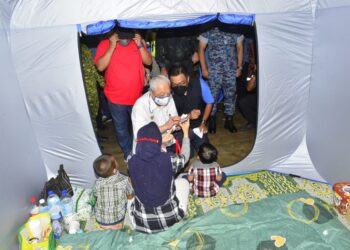 SEORANG mangsa banjir menunjukkan gambar rumahnya yang dilanda banjir kepada Ismail Sabri Yaakob ketika Perdana Menteri melawat PPS SJKC)Mentakab di Mentakab, Temerloh, Pahang. - UTUSAN/SHAIKH AHMAD RAZIF