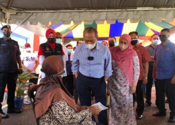 MUHYIDDIN Yassin (tengah) bersama isteri, Puan Sri Norainee Abdul Rahman berbual dengan seorang penerima vaksin yang sedang menunggu giliran di PPV Dewan Muafakat Bukit Gambir di Tangkak, Johor. - UTUSAN/NUR ALINA HASSAN