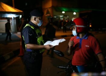 PEGAWAI polis memeriksa seorang penduduk di sekitar Bukit Tinggi, Klang berikutan PKPB yang berkuat kuasa selepas jam 12 malam semalam. - FOTO/ZULFADHLI ZAKI