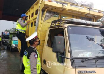 ANGGOTA polis memeriksa kenderaan yang melalui pintu tol Cikupa di Tangerang, Indonesia. - AGENSI