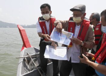 AHMAD Zakiyuddin Abdul Rahman menunjukkan pelan tambakan laut perairan selatan sewaktu menaiki bot meninjau tapak tambakan itu di Permatang Damar Laut, Bayan Lepas, Pulau Pinang.