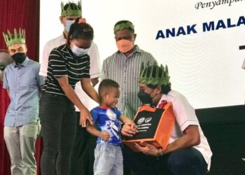 KHAIRY Jamaluddin (kanan) menyampaikan Anugerah Anak Malaysia Sihat kepada anak Orang Asli pada Pelancaran Tinjauan Kesihatan Orang Asli di Dewan Komuniti Sahom, Kampar, Perak, hari ini. - FOTO/LIYANA RAMLI