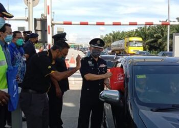 CHONG Boo Khim (kiri) menyerahkan cenderahati kepada pengguna kenderaan di Plaza Tol Sitiawan Utara WCE sempena Operasi Selamat 18 Aidilftri 2022 Daerah Manjung, Lumut, Perak, hari ini.