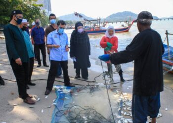 CHE ABDULLAH Mat Nawi bertanyakan sesuatu kepada seorang nelayan di Teluk Kumbar, Pulau Pinang yang bakal terjejas secara langsung ekoran rancangan tambak laut di perairan selatan negeri itu (PSR).