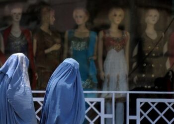 DUA wanita Afghanistan berjalan di hadapan kedai yang meletakkan patung pameran di Kabul.-AFP