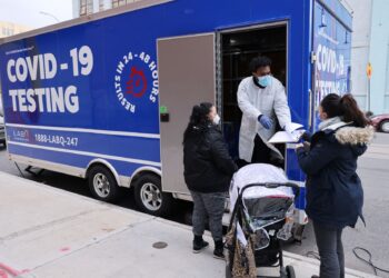 PETUGAS kesihatan berdiri di makmal bergerak ujian Covid-19 di Brooklyn.-AFP