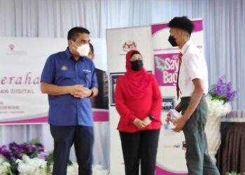 RADZI Jidin (kiri) memperkata sesuatu kepada seorang pelajar yang menerima peranti digital pada Program Penyerahan Peranti Pendidikan Digital AEON Sayap Bagimu di SMK Kelibang, Langkawi, Kedah, hari ini. - UTUSAN/NUR AMALINA AZMAN