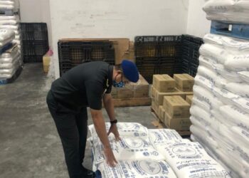 PEGAWAI KPDNHEP Perak memeriksa tepung gandum yang disita dalam operasi di kawasan perindustrian di Menglembu, Ipoh, Perak, semalam.- IHSAN KPDNHEP PERAK