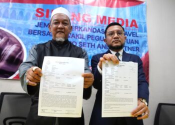 MOHD. Hanif Mohd. Salleh (kiri) bersama Muhammad Nazrin Mohd. Seth menunjukkan laporan polis berhubung kes kumPulan haji terkandas di Bandar Baru Bangi, Selangor, semalam. - UTUSAN/AMIR KHALID