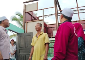 IDRIS Ahmad (kiri) melihat keadaan rumah penduduk yang rosak akibat ribut di Bagan Serai hari ini. - UTUSAN/WAT KAMAL ABAS