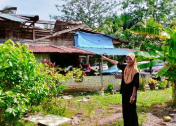 SEORANG penduduk menunjukkan bumbung rumahnya yang diterbangkan angin akibat ribut petang semalam di Kampung Parit Sulaiman, Bagan Serai. - UTUSAN/WAT KAMAL ABAS