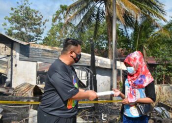 TUANKU Syed Faizuddin Putra Jamalullail (kiri) menyampaikan sumbangan kepada Iswahanim Amran di Kampung Seri Sepakat, Titi Tinggi, Padang Besar, Perlis, hari ini.