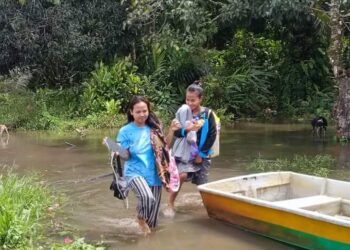 DUA MANGSA menaiki bot untuk dibawa berpindah ke PPS balai raya Kampung Denai di Rompin, Pahang. - FOTO/IHSAN JBPM PAHANG