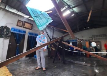 NURUL Syafika Abd. Ghani melihat bumbung rumah yang rosak serta kayu alang yang menimpanya dalam kejadian ribut di Kampung Ulu Mahang, Kulim, Kedah semalam. - FOTO/AZAHAR HASHIM