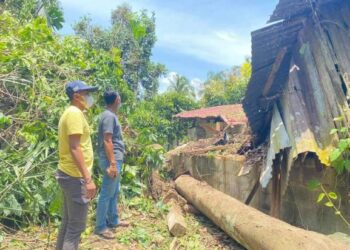 MOHD. Zakwan Abdullah (depan) bersama Mohd. Podzi Saleh melihat sebahagian rumah rosak teruk dihempap sebatang pokok di Kampung Berahmah di Lipis, Pahang. - FOTO/HARIS FADILAH AHMAD