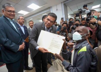 SAIFUDDIN Nasution Ismail menyerahkan surat permohonan kewarganegaraan kepada warga emas, V. Munisamy di JPN, Putrajaya. - UTUSAN/FAISOL MUSTAFA