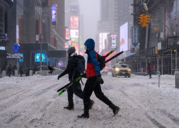 PEJALAN kaki membawa peralatan ski semasa melalui kawasan jalan di New York.-AFP