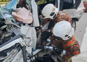 ANGGOTA bomba mengeluarkan mangsa dalam kemalangan di Kilometer 358.7, Lebuh Raya Utara-Selatan arah utara dekat Tapah hari ini. - UTUSAN/JBPM PERAK