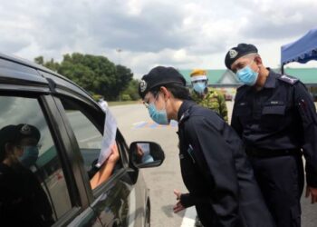 NURULHUDA Mohd. Salleh memeriksa surat kebenaran rentas sempadan seorang pengguna jalan raya dalam sekatan jalan raya di Plaza Tol Bukit Raja, Klang, Selangor, hari ini. - FOTO/ISKANDAR SHAH MOHAMED