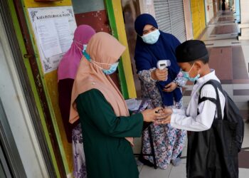 Guru sekolahmerlakukan proses sanitasi pada tangan dan mengimbas bacaan suhu badan pada pelajar bagi mematuhi prosedur operasi standard (SOP) - UTUSAN/FAUZI BAHARUDIN