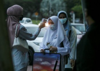 Pelajar Tingkatan 5  Sekolah Menengah Kebangsaan Bukit Jelutong di Shah Alam, Selangor diperiksa suhu badan semasa hadir ke sekolah pada 20 Januari 2020.- UTUSAN/ZULFADHLI ZAKI