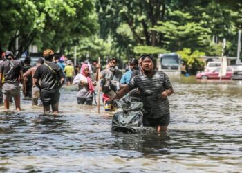 MANGSA banjir meranduk air ke rumah mereka yang ditenggelami air untuk melihat situasi dan barangan yang boleh diselamatkan di Taman Sri Muda, Shah Alam Selangor, kelmarin. - UTUSAN/AFIQ RAZALI