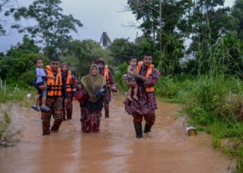 SURIATI Yusof (tengah) bersama dua anaknya termasuk Adib Arshad Abdul Halim, 16 bulan, (kanan, didukung anggota bomba) yang hampir lemas selepas terjatuh dari kerusi di ruang tamu rumahnya di Kampung Petaling di Kuala Nerus, Terengganu yang dinaiki air separas paha. - FOTO/PUQTRA HAIRRY ROSLI