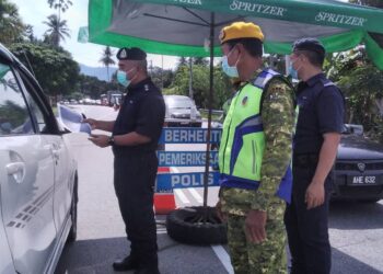 OSMAN Mamat memeriksa dokumen pemilik kenderaan dalam SJR di Taiping, Perak, hari ini. - UTUSAN/WAT KAMAL ABAS