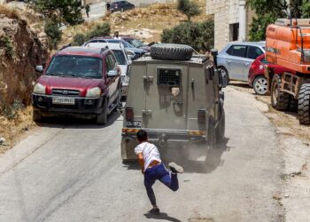 REMAJA Palestin membaling batu ke arah kenderaan tentera Israel di Tebing Barat. - AFP