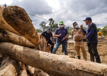 PENGARAH Jabatan Perhutanan Negeri Pahang, Mohd. Hizamri Mohd. Yasin (dua dari kiri) mendengar penerangan mengenai timbunan kayu yang terkumpul akibat banjir ketika melawat ke kawasanTelemong di Karak. – UTUSAN/SHIDDIEQIIN ZON