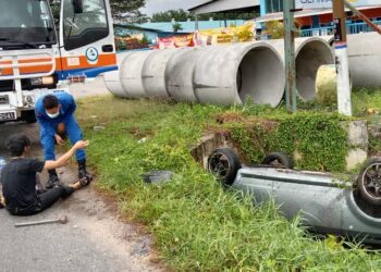 ANGGOTA APM menyelamatkan lelaki yang terperangkap dalam keretanya yang terbabas ke dalam parit Jalan Teluk Intan-Hutan Melintang di Bagan Datuk, Perak, hari ini.