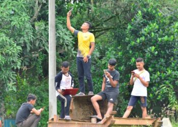 PENDUDUK terpaksa mengangkat tinggi telefon mereka untuk mendapatkan talian internet yang jelas di Kota Shahbandar, Rompin, Pahang. – FOTO/SHAIKH AHMAD RAZIF