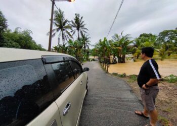 IZUWAN M. Yusuf menunjukkan laluan ke rumah ibunya di Kampung Tengah, Gemencheh, Tampin yang tidak boleh dilalui selepas dinaiki air sejak awal pagi tadi. - UTUSAN/NOR AINNA HAMZAH