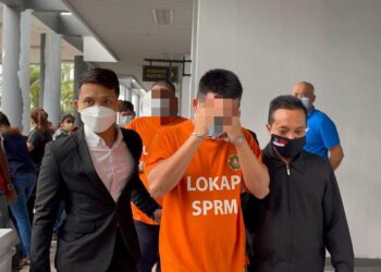 DUA suspek yang memakai baju lokap SPRM dibawa keluar dari Mahkamah Ayer Keroh, Melaka selepas permohonan reman selesai kira-kira pukul 10 pagi. - UTUSAN