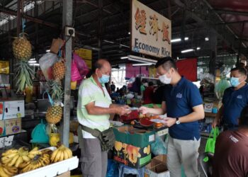 OH TONG KEONG menyerahkan pelitup muka kepada penjaja di pasar awam Batu Maung, Pulau Pinang dalam program kesedaran mengenai penularan pandemik Covid-19.