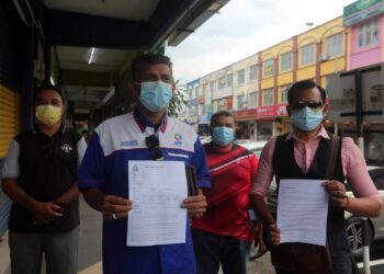 HASSAN Kuthoos (dua dari kiri) menunjukkan laporan polis berhubung bantahan penamatan PKPD di asrama pekerja Top Glove  yang dibuat di Balai Polis Meru, Klang, Selangor petang ini. -Foto ISKANDAR SHAH MOHAMED