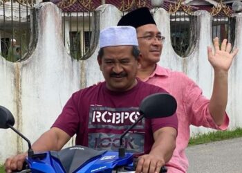 MOHD. Zubir Embong (belakang) menunggang motosikal ketika berkempen pada PRU15 di Kuala Terengganu, semalam. - FOTO/KAMALIZA KAMARUDDIN