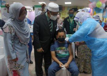 ALIAS Razak (dua dari kiri) melihat seorang kanak-kanak menerima suntikan dalam Program Imunisasi Covid-19 Kanak-Kanak (PICKids) di Hospital Sultanah Nur Zahirah (HSNZ) di Kuala Terengganu, hari ini. - FOTO/PUQTRA HAIRRY ROSLI