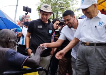 MAHATHIR Mohamad (kanan) bersama Rafique Rashid (dua dari kanan) memberikan lencana kepada seorang pengunjung OKU pasar malam Seksyen 24, Shah Alam, Selangor.-UTUSAN/ MOHAMAD NAUFAL MOHAMAD IDRIS