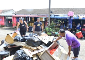 RAKYAT bergotong-rotong membuang barangan rumah yang rosak akibat banjir di kawasan perumahan Inderapura di Kuantan, Pahang. - UTUSAN/SHAIKH AHMAD RAZIF