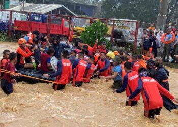 PASUKAN penyelamat membantu menyelamatkan penduduk yang terjejas akibat kawasan kediaman dilanda banjir di bandar Cagayan de Oro.-AFP