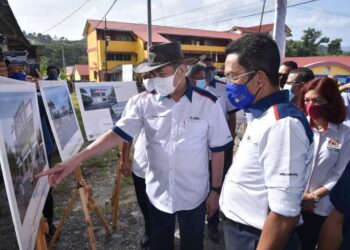 WAN Junaidi Tuanku Jaafar (kiri) dan Jalaluddin Alias melihat ilustrasi projek pembangunan kedai koperasi UDA Niaga selepas menyempurnakan Majlis Pecah Tanah Pembinaan Kedai Dua Tingkat Di Atas Tanah Koperasi Kakitangan Kerajaan Daerah Jelebu di Kuala Klawang, Jelebu, hari ini.