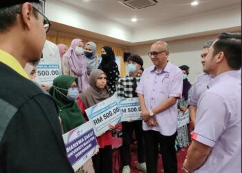 MAZLAN Abd. Ghaffar  (tengah) menyantuni pelajar penerima zakat selepas majlis agihan kepada mereka, baru-baru ini.