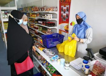 NUR Syahidah Mohamad melayan pelanggan yang membeli produk makanan di kedainya, Bunga Manis Frozen Mart di Seremban 2, Seremban. – FOTO/ZAKKINA WATI AHMAD TARMIZI