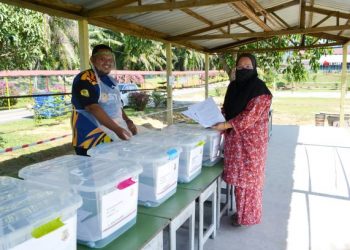 HAZNANI Mansor mengambil lembaran kerja bagi anaknya yang disediakan pihak SK Labu untuk mengikuti PdPR.-UTUSAN/ZAKKINA WATI AHMAD TARMIZI.