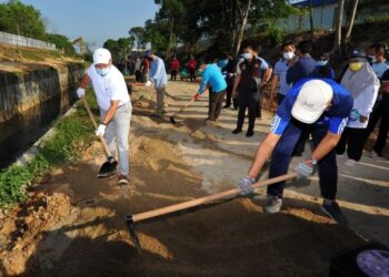 HASNI Mohammad (kiri) bersama sukarelawan membersihkan kawasan yang akan dijadikan taman rekreasi sempena Program Gotong Royong  Sayangi Sungai Kim Kim di Pasir Gudang, Johor. -UTUSAN/RAJA JAAFAR ALI